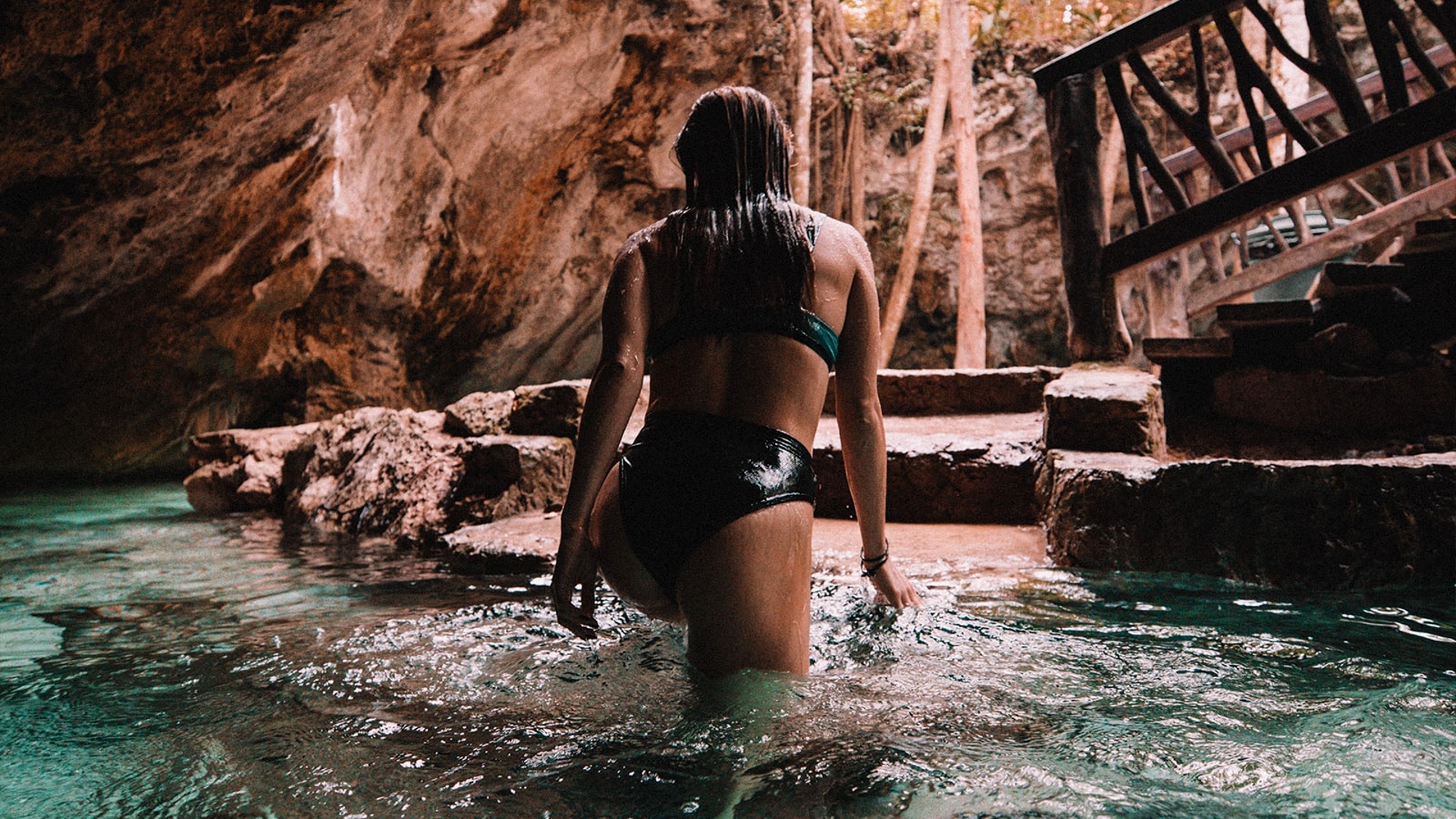 Mujer en bikini saliendo de un río subterraneo