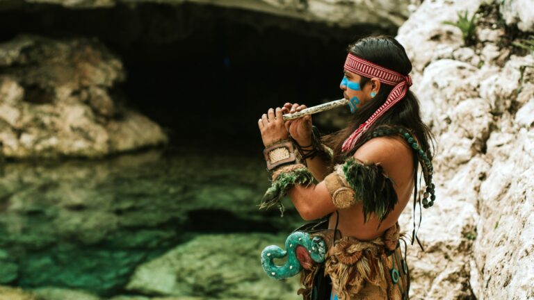 Hombre maya toca una flauta junto a un cenote