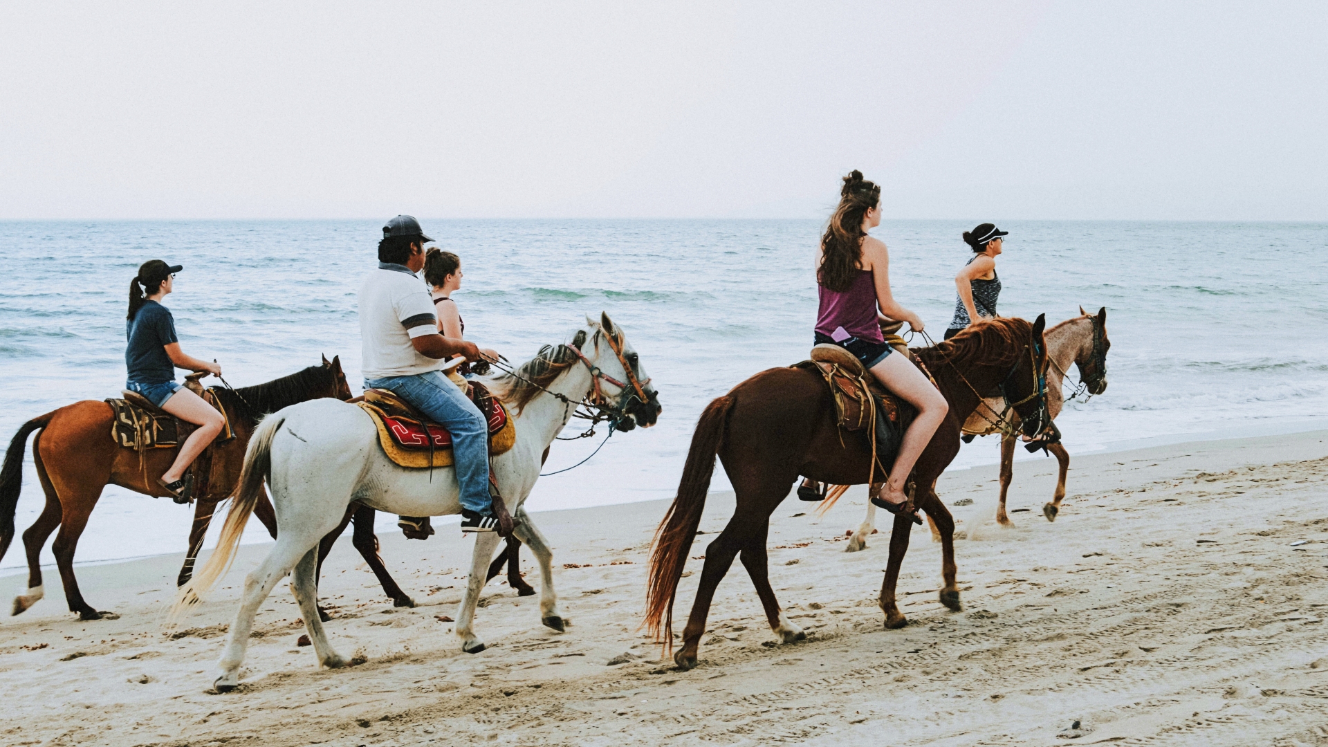 Jinetes paseando a caballo por la playa