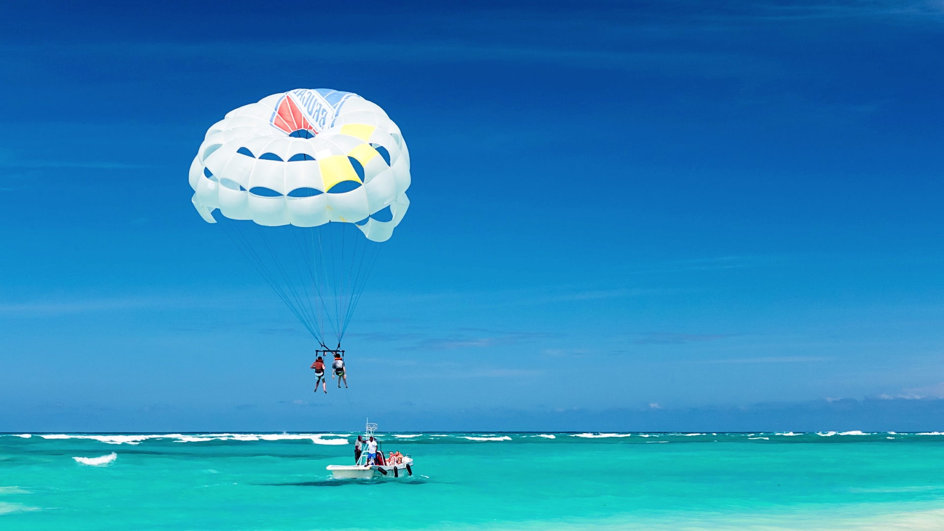 Personas haciendo parasailing en una playa de Punta Cana