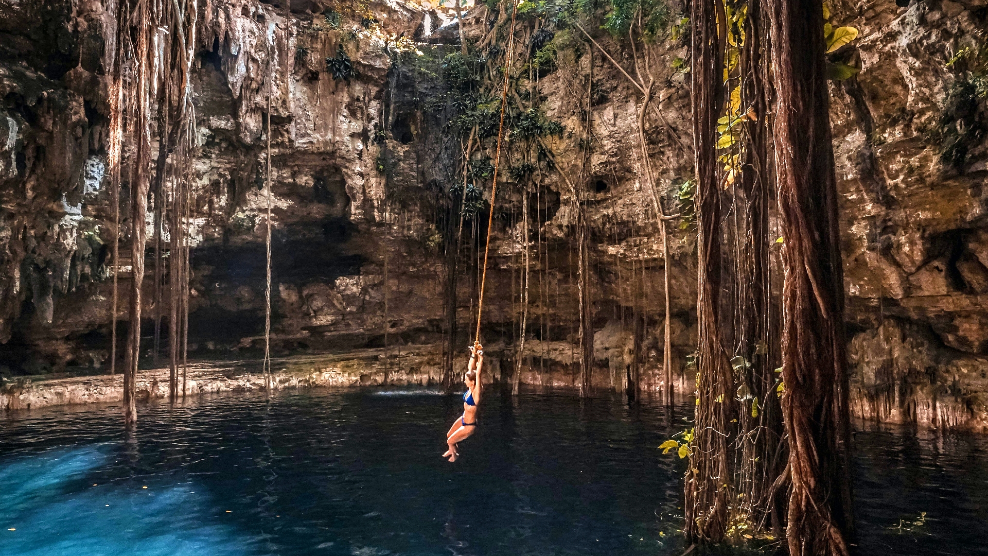 Mujer balanceándose en un columpio en el interior de un cenote