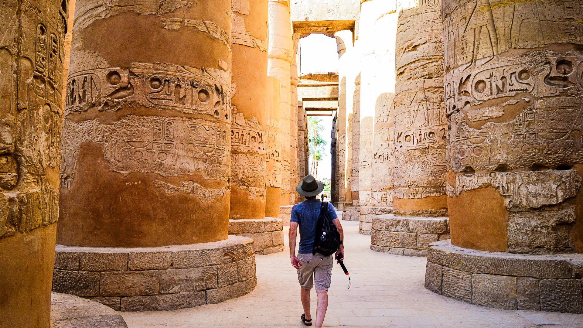 Turista caminando entre las columnas más grandes de la sala Hipóstila de Karnak