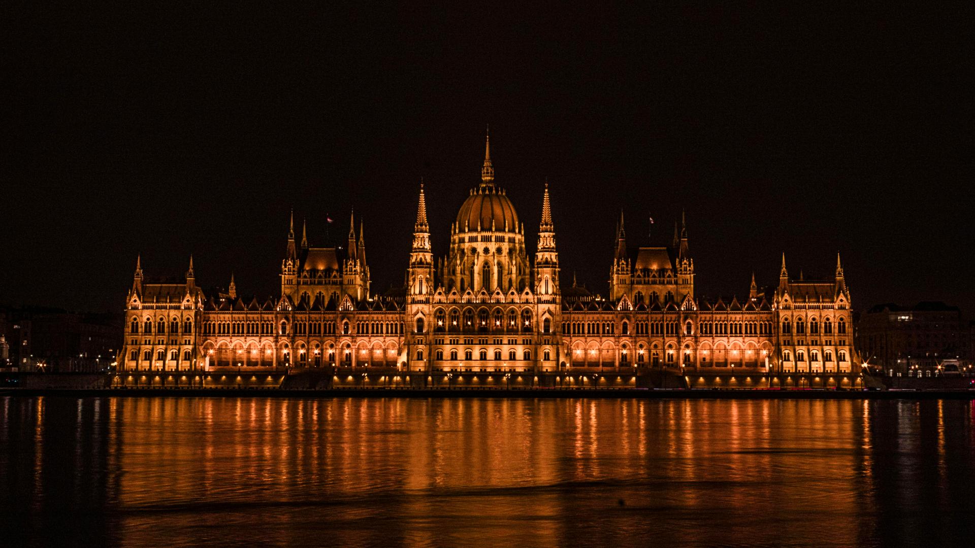 Parlamento de Budapest iluminado en la noche fotografiado desde el lado opuesto del Danubio