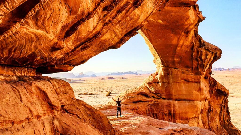 Turista posa en un arco de piedra en el desierto de Wadi Rum