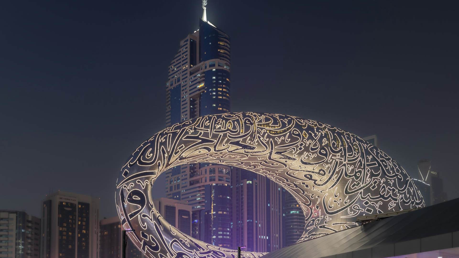 Fachada del Museo del Futuro iluminada con el Burj Khalifa de fondo