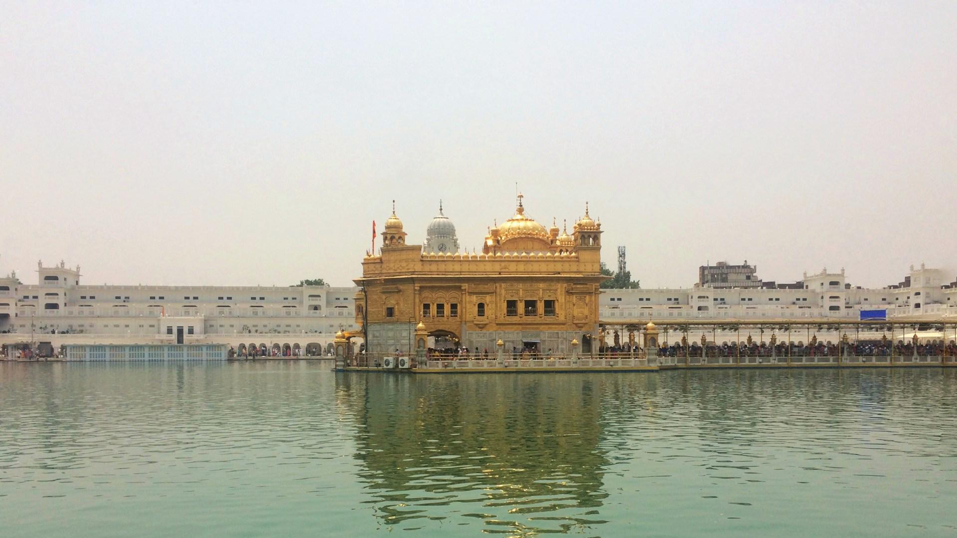 Vista de frente del Templo Dorado de Amritsar rodeado de peregrinos